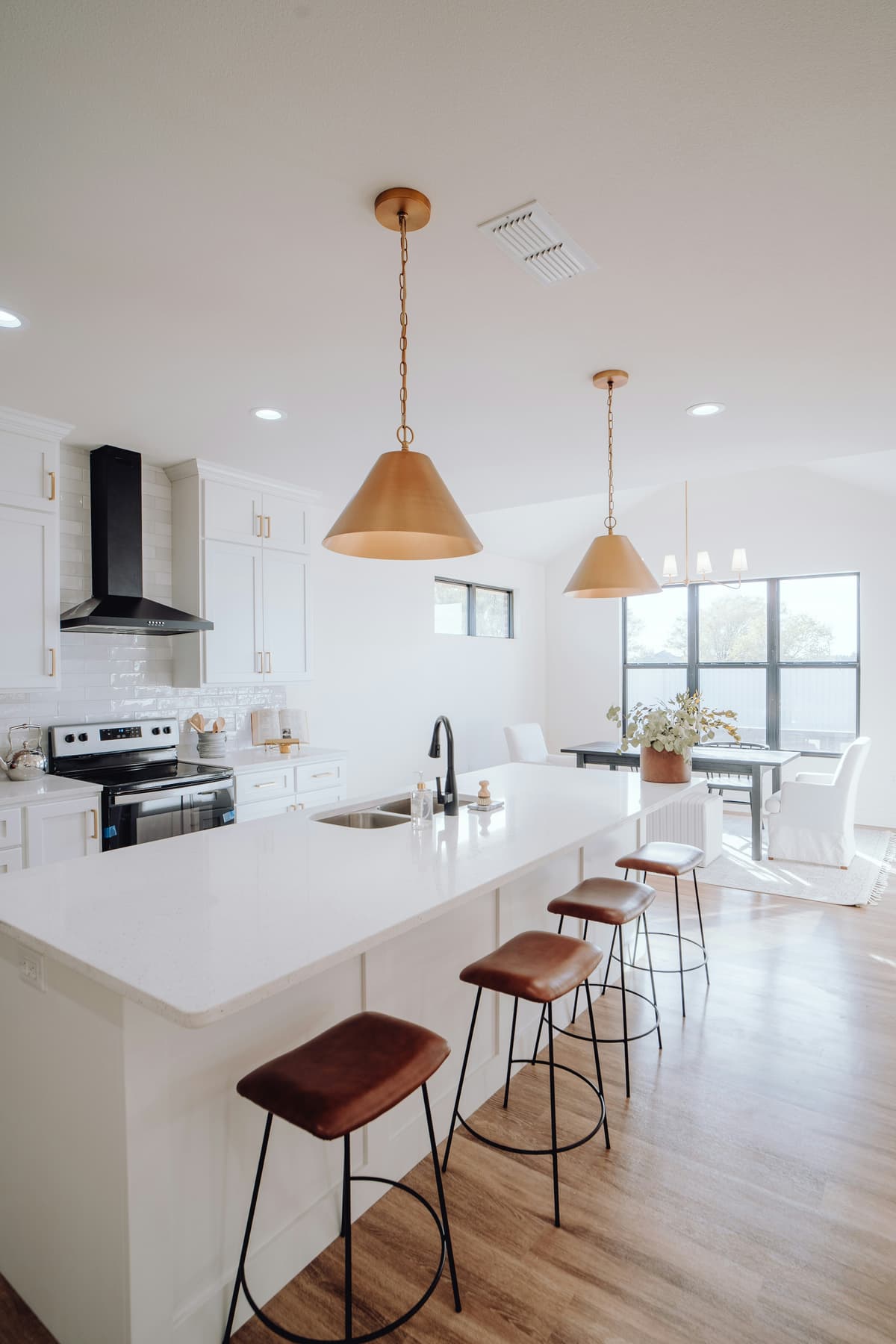 Bright kitchen with white painted walls, brass pendant lights and island